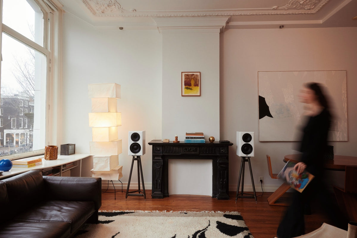 The TrueTone Story: a pair of white speakers on tripod stands either side of a black fireplace in a light living room